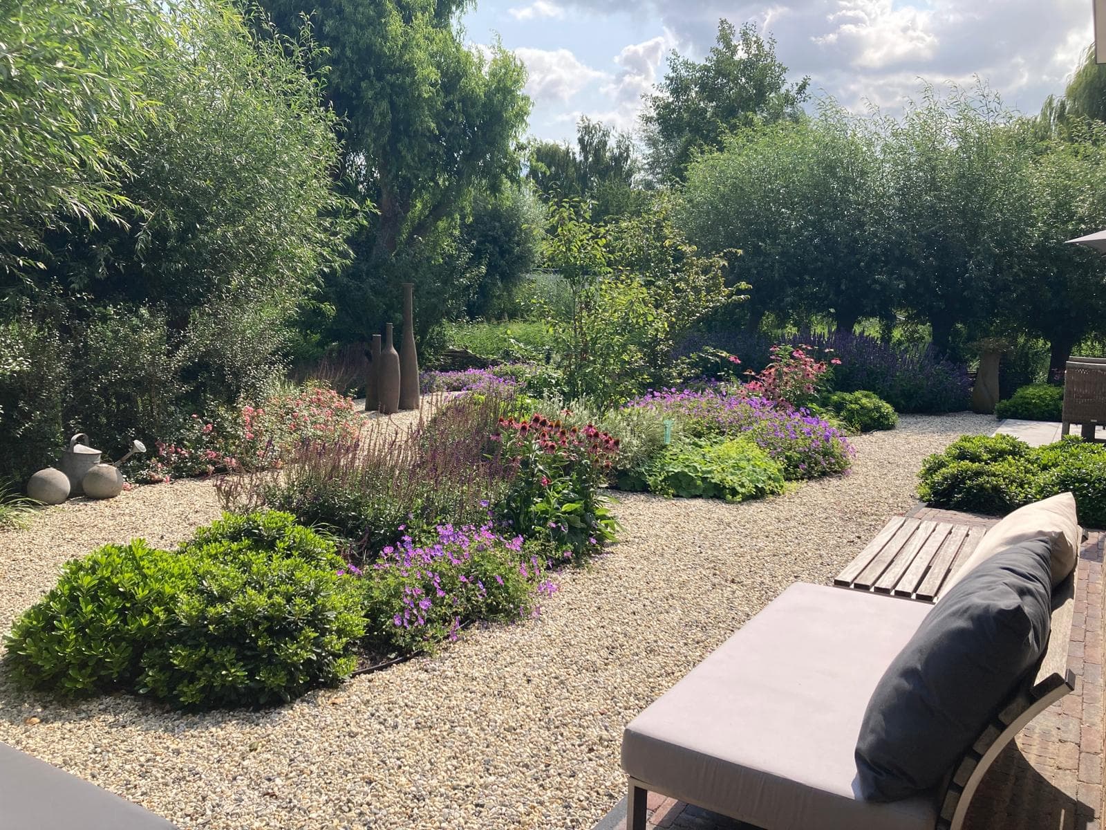 Prachtig aangelegde tuin met kleurrijke bloemen, grindpaden en zithoek door Luijk Tuinprojecten